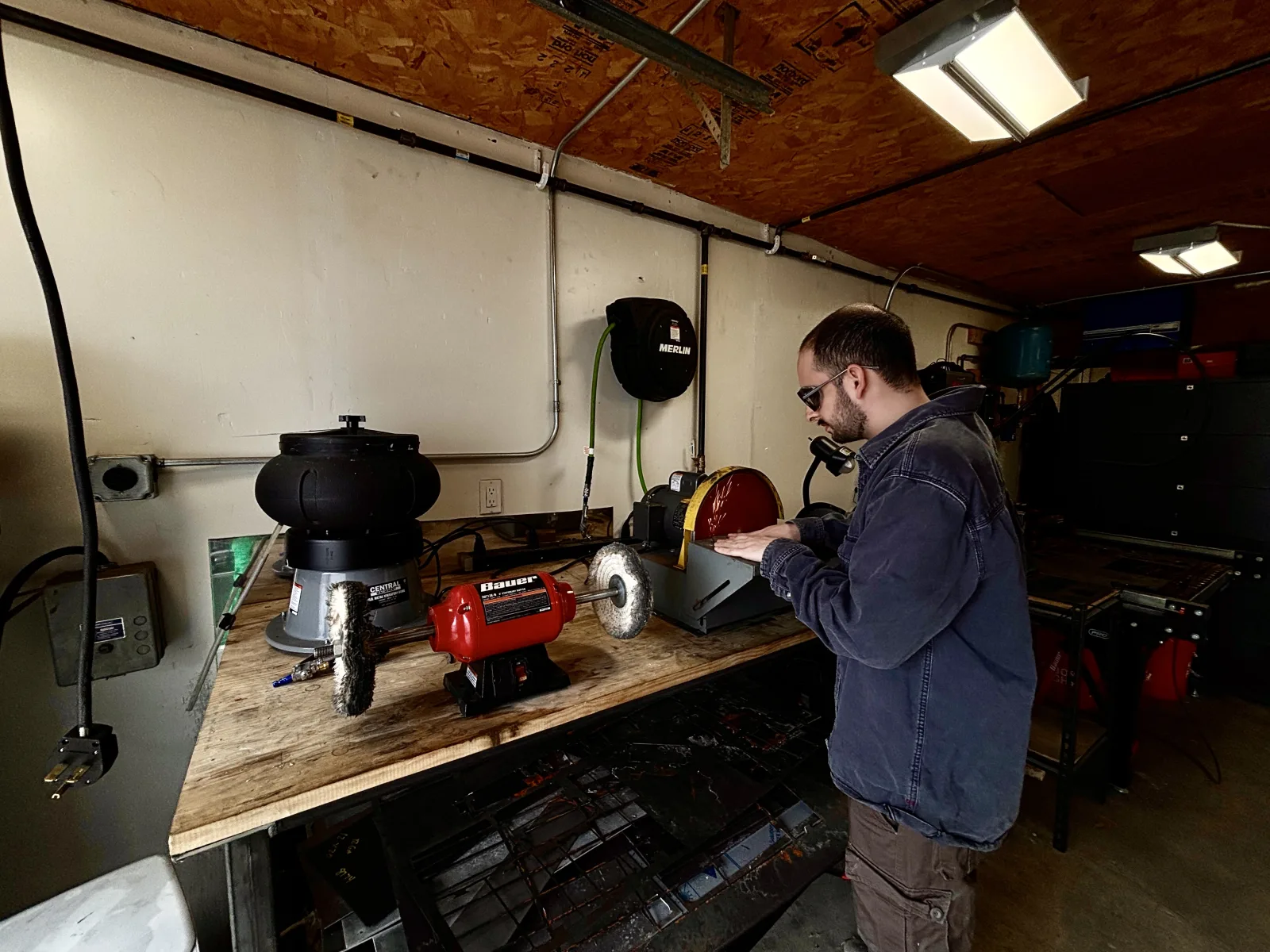 Wide angle view of Nathan grinding metal in the Arinta Engineering shop